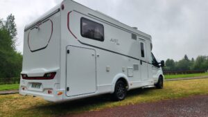 Camping-car blanc stationné sur pelouse verdoyante
