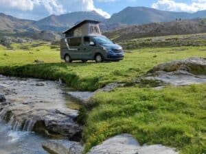 Van aménagé près d’un ruisseau en montagne