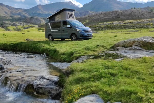 Van aménagé près d’un ruisseau en montagne