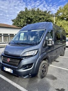 Fourgon aménagé bleu stationné sur parking extérieur