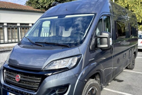 Fourgon aménagé bleu stationné sur parking extérieur