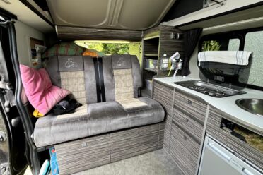 Ausgestatteter Innenraum eines Campervans mit Sitzbank und Küchenzeile