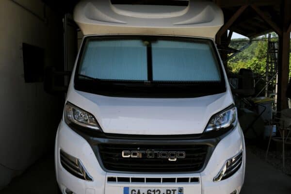Camping-car blanc garé sous un abri en bois
