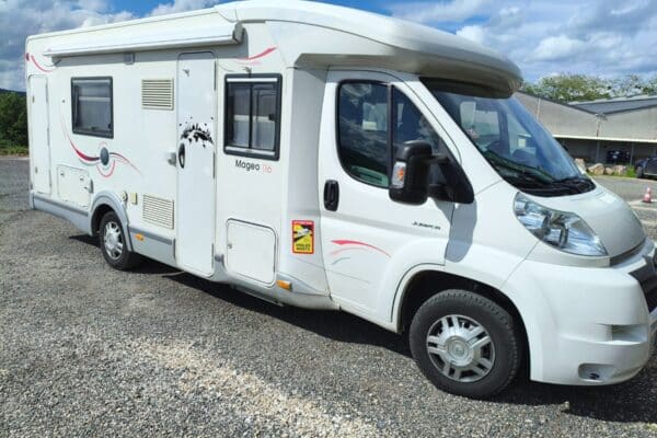 Camping-car blanc stationné sur terrain gravillonné