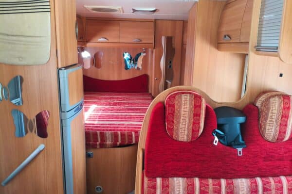 Intérieur de camping-car avec lit et banquettes rouges