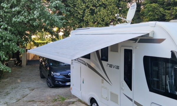 Camping-car avec store déployé dans une cour