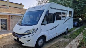 Camping-car blanc stationné devant une maison