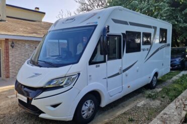Camping-car blanc stationné devant une maison