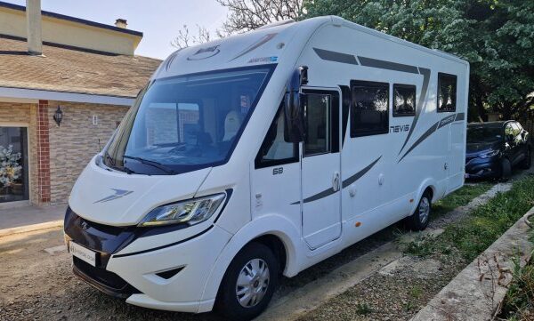 Camping-car blanc stationné devant une maison