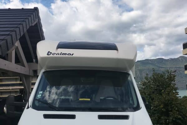 Camping-car blanc Benimar garé près des montagnes