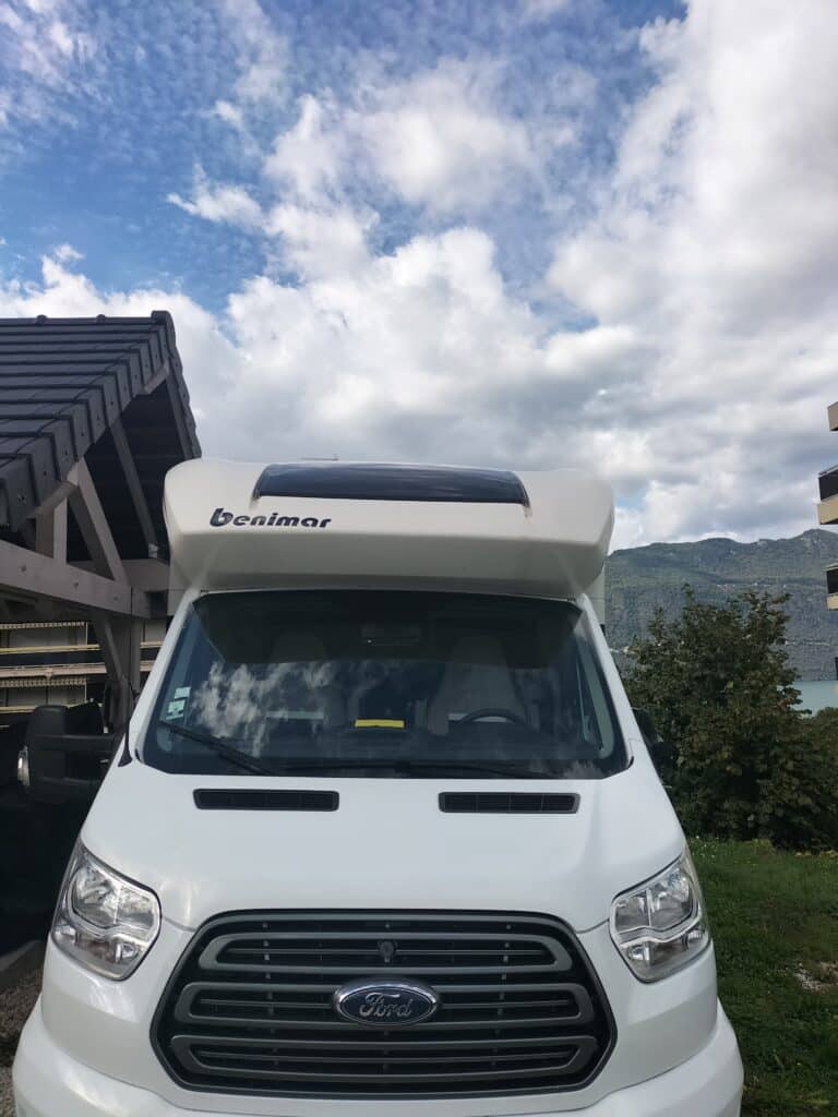 Camping-car blanc Benimar garé près des montagnes