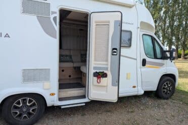 Camping-car blanc porte ouverte en pleine nature