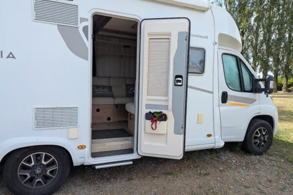 Camping-car blanc porte ouverte en pleine nature
