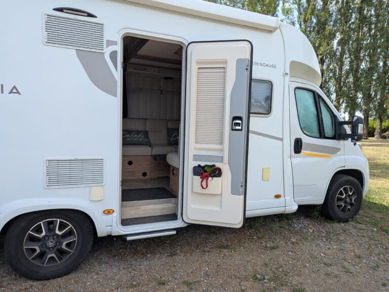 Camping-car blanc porte ouverte en pleine nature