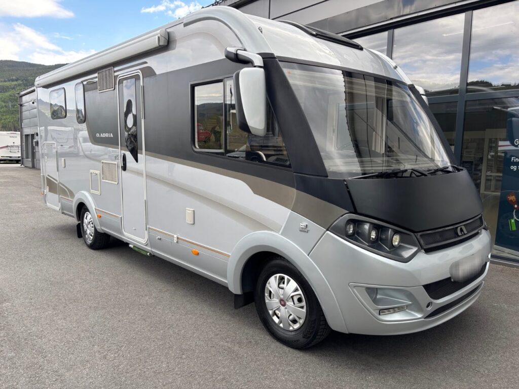 Camping-car gris et blanc stationné devant bâtiment