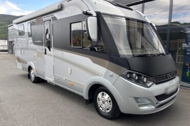 Camping-car gris et blanc stationné devant bâtiment