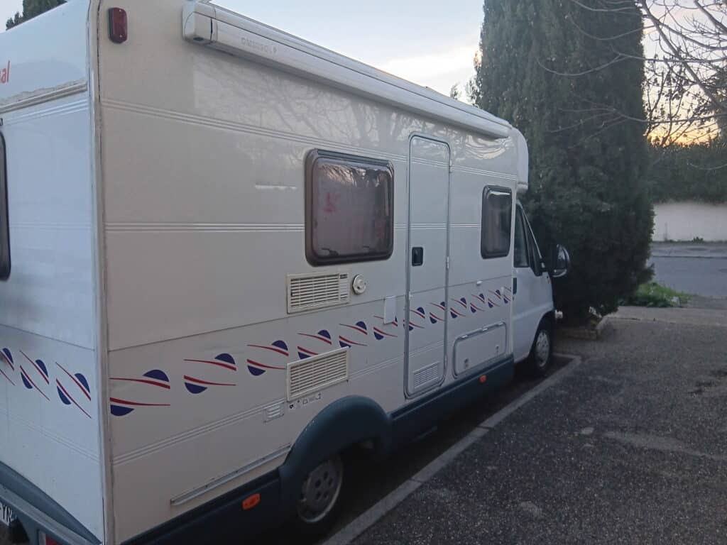 Camping-car blanc stationné au bord d’une rue
