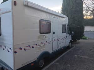 Camping-car blanc stationné au bord d’une rue