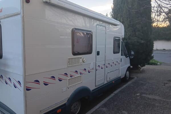 Camping-car blanc stationné au bord d’une rue