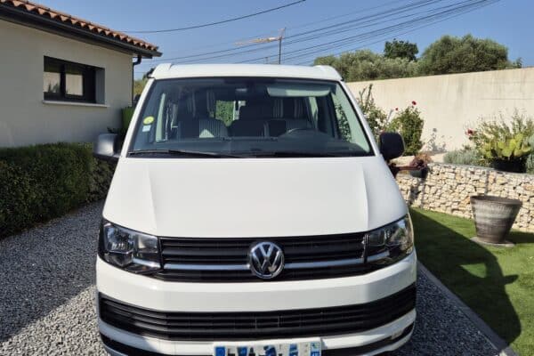 Van Volkswagen blanc garé devant une maison