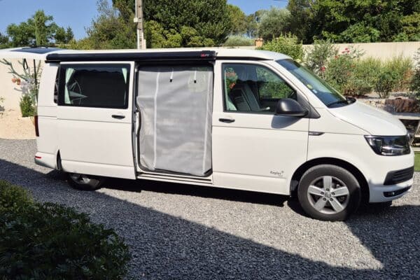 Van aménagé blanc garé avec porte ouverte