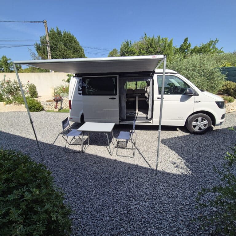 Van aménagé blanc avec auvent et table extérieure