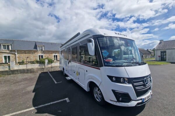 Camping-car blanc stationné dans un village rural