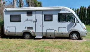 Camping-car blanc stationné sur pelouse ensoleillée
