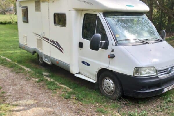Camping-car blanc stationné sur pelouse verdoyante