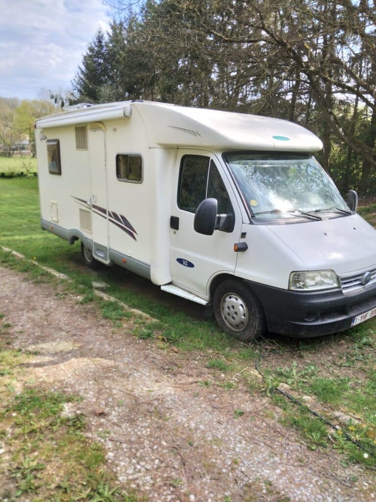 Camping-car blanc stationné sur pelouse verdoyante