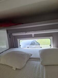 Lit de camping-car avec fenêtre et étagère