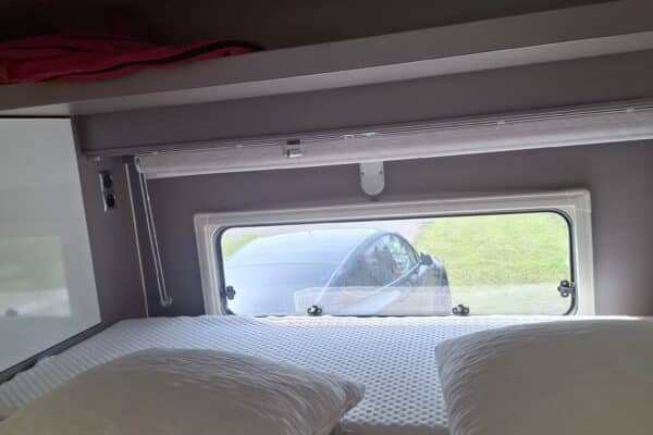 Lit de camping-car avec fenêtre et étagère