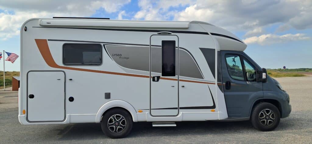 Camping-car blanc et gris stationné en bord de route