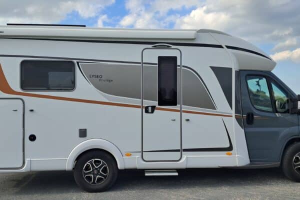 Camping-car blanc et gris stationné en bord de route