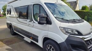 Camping-car blanc stationné dans un quartier résidentiel