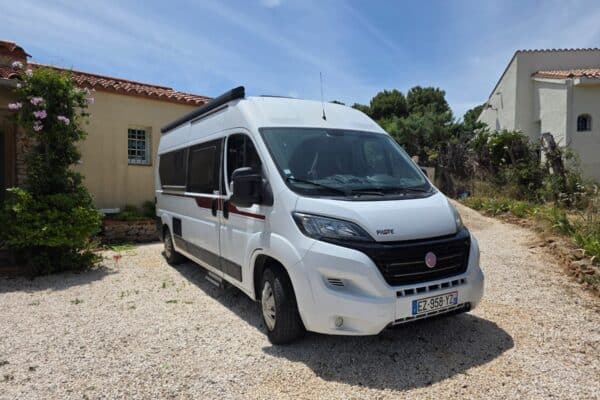 Fourgon aménagé blanc garé devant maison méditerranéenne