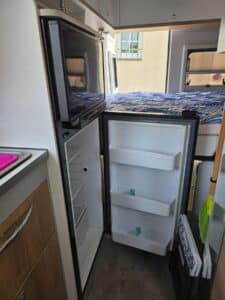 Intérieur camping-car avec réfrigérateur ouvert et lit