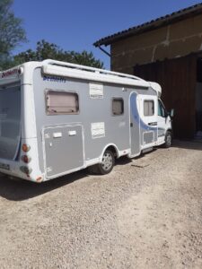 Camping-car blanc stationné sur terrain gravillonné