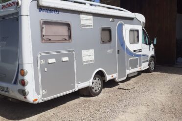 Camping-car blanc stationné sur terrain gravillonné