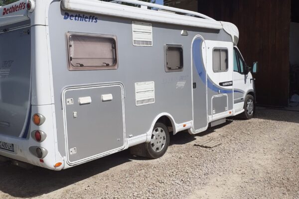 Camping-car blanc stationné sur terrain gravillonné