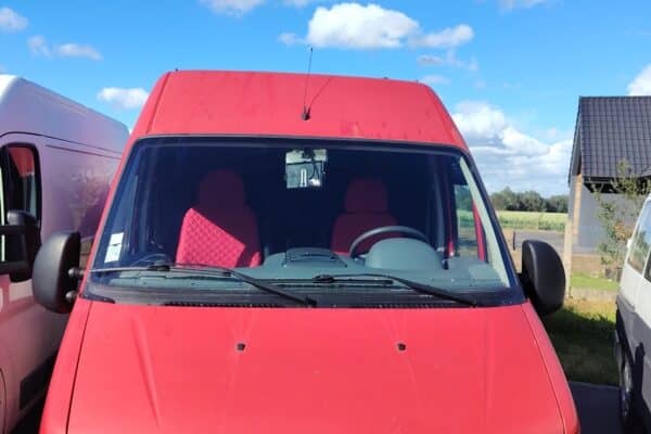 Camionnette rouge garée sous ciel bleu