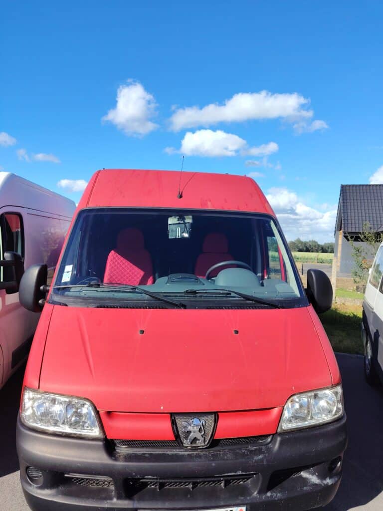 Camionnette rouge garée sous ciel bleu
