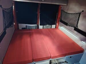 Lit aménagé dans un van avec matelas rouges