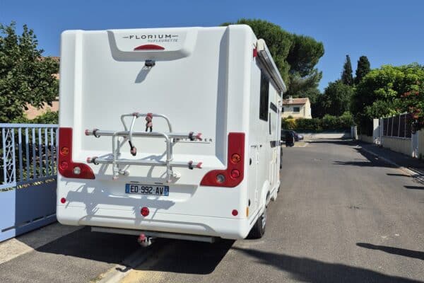 Camping-car blanc garé dans rue résidentielle ensoleillée