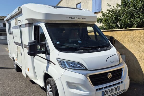 Camping-car blanc stationné dans rue résidentielle ensoleillée