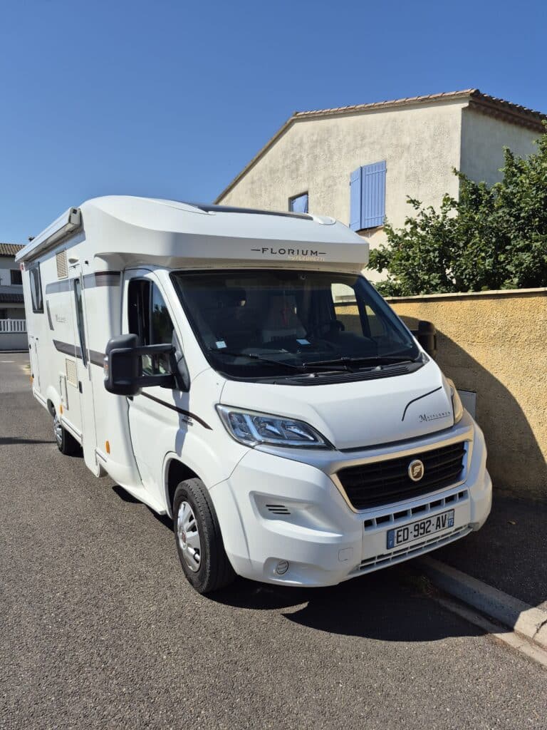 Camping-car blanc stationné dans rue résidentielle ensoleillée