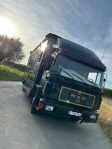 Camion aménagé noir stationné au coucher du soleil