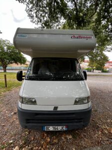 Camping-car blanc Challenger stationné sous des arbres