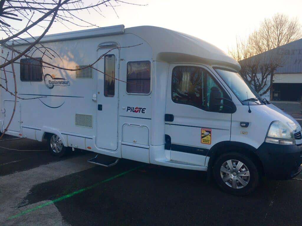Camping-car blanc stationné en extérieur au coucher du soleil