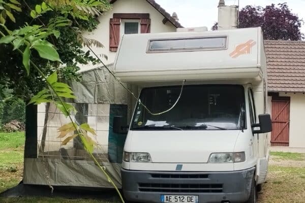 Camping-car blanc avec auvent dans un jardin